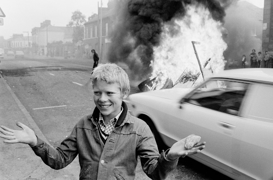 Chris Steele Perkins ~ Northern Ireland. West Belfast. Catholic area. Youth with a stone during a riot at the top of Leeson Street