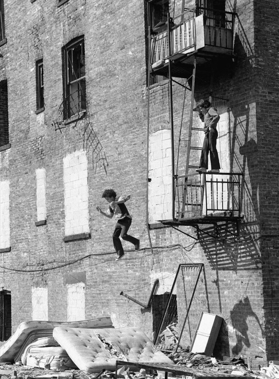 Martha Cooper ~ A boy jumping onto a mattress from a fire escape. Lower East Side